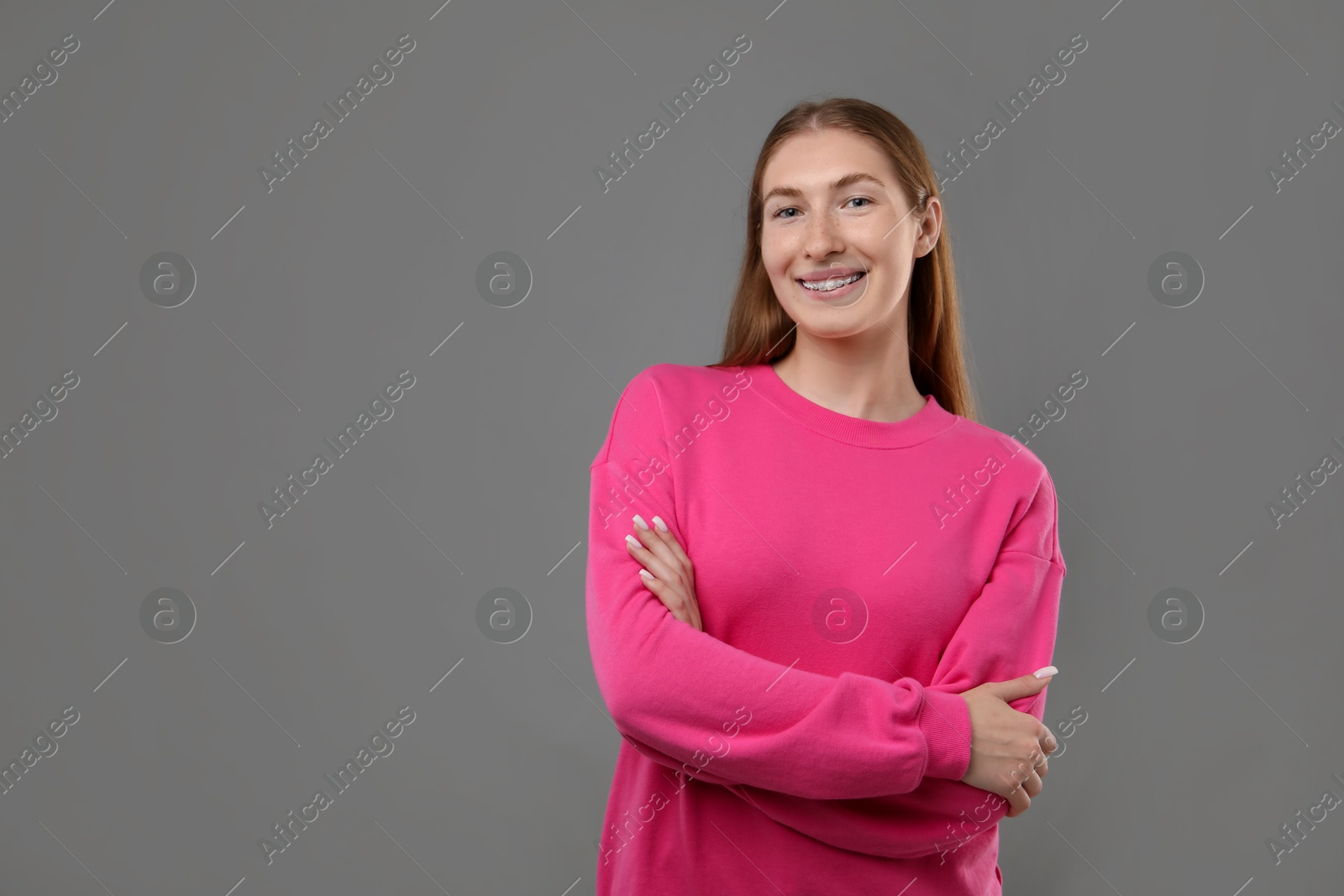 Photo of Smiling girl with braces on grey background, space for text