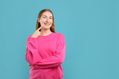 Photo of Girl pointing at her braces on light blue background, space for text