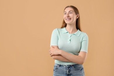 Photo of Smiling girl with braces on beige background, space for text