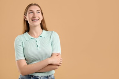 Photo of Smiling girl with braces on beige background, space for text