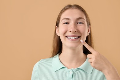 Photo of Girl pointing at her braces on beige background