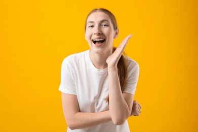 Photo of Smiling girl with braces on orange background