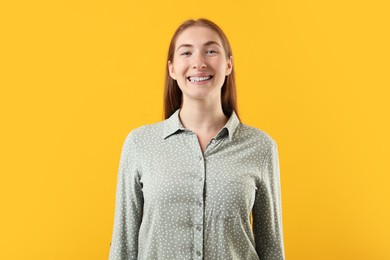 Photo of Smiling girl with braces on orange background