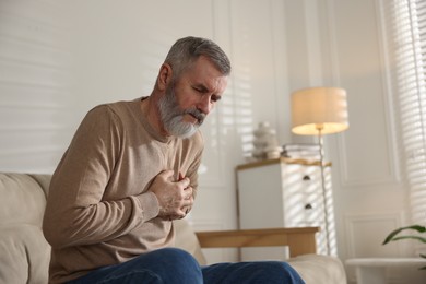 Photo of Senior man suffering from pain in chest at home