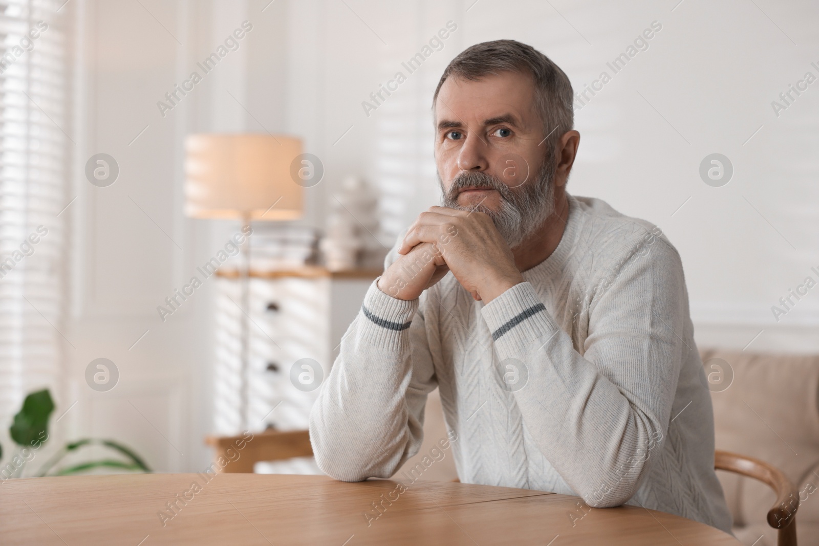 Photo of Senior man at table indoors, space for text