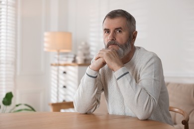 Photo of Senior man at table indoors, space for text