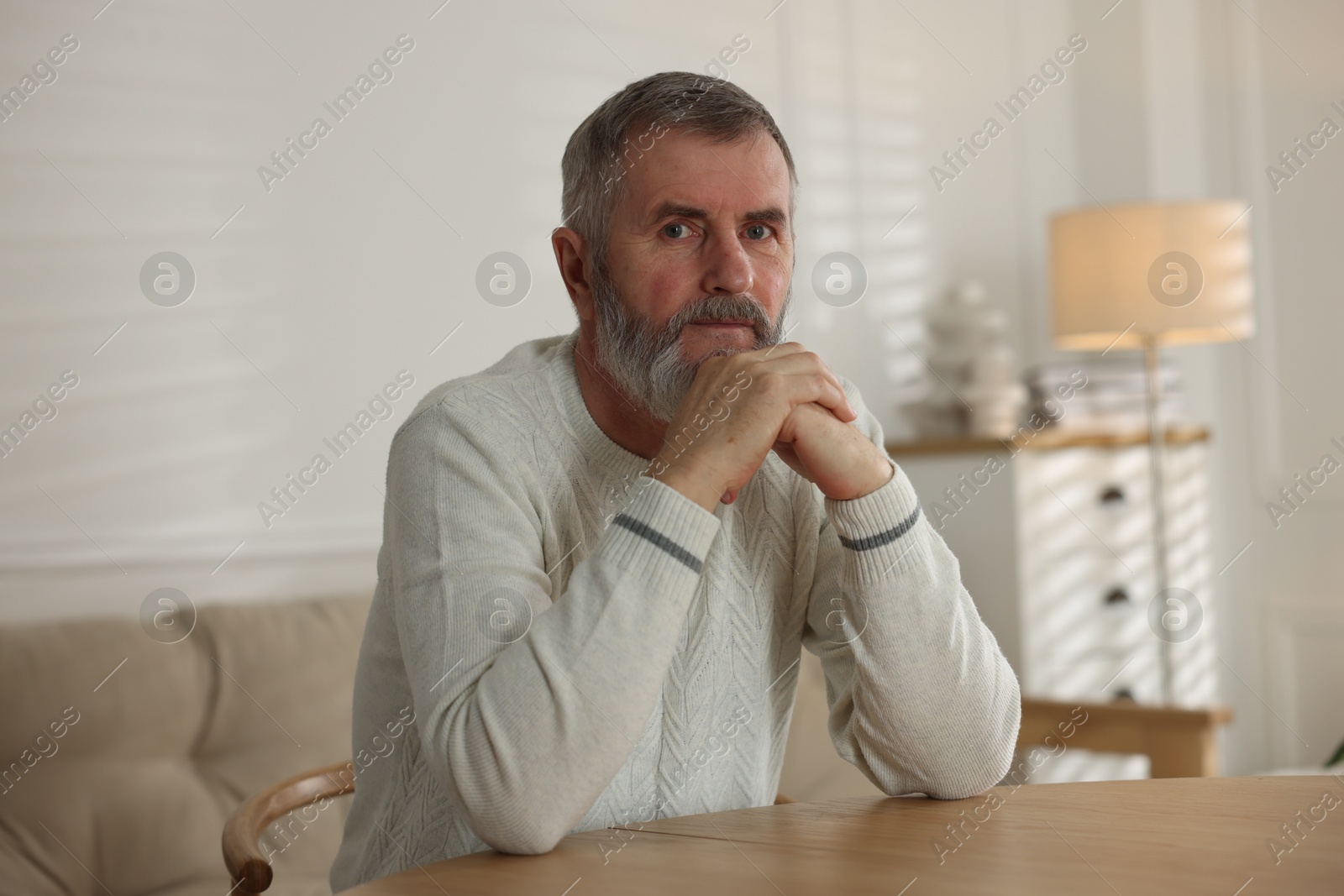 Photo of Portrait of senior man at table indoors