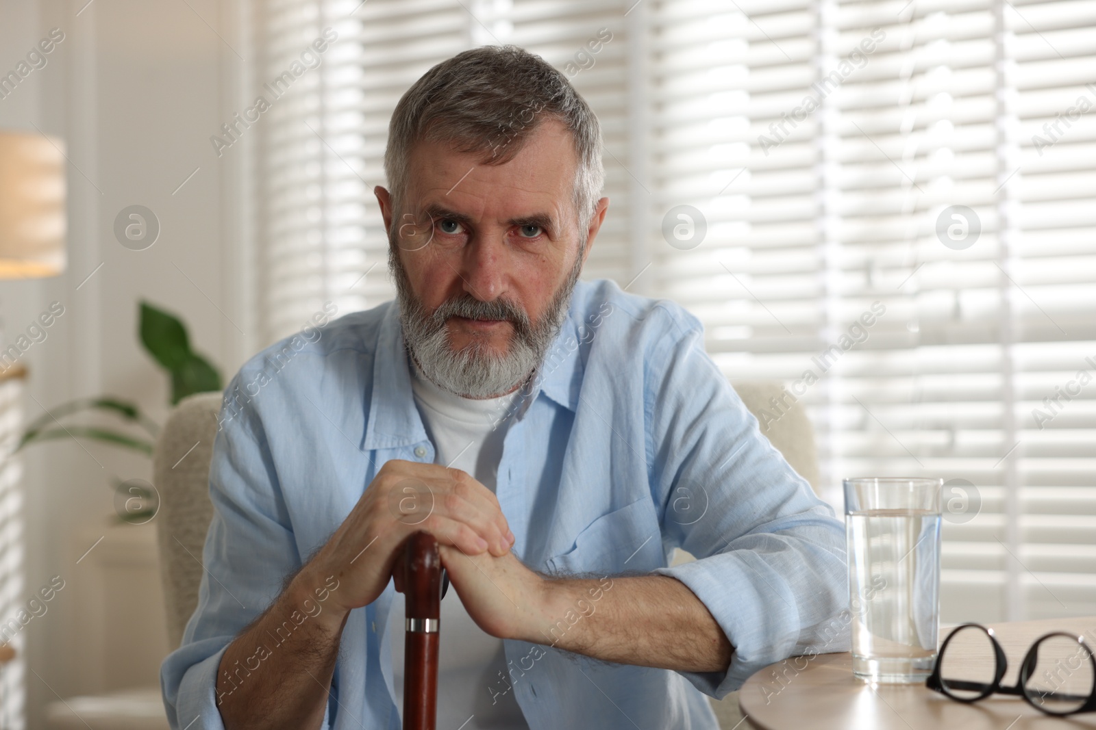 Photo of Senior man with walking cane at home