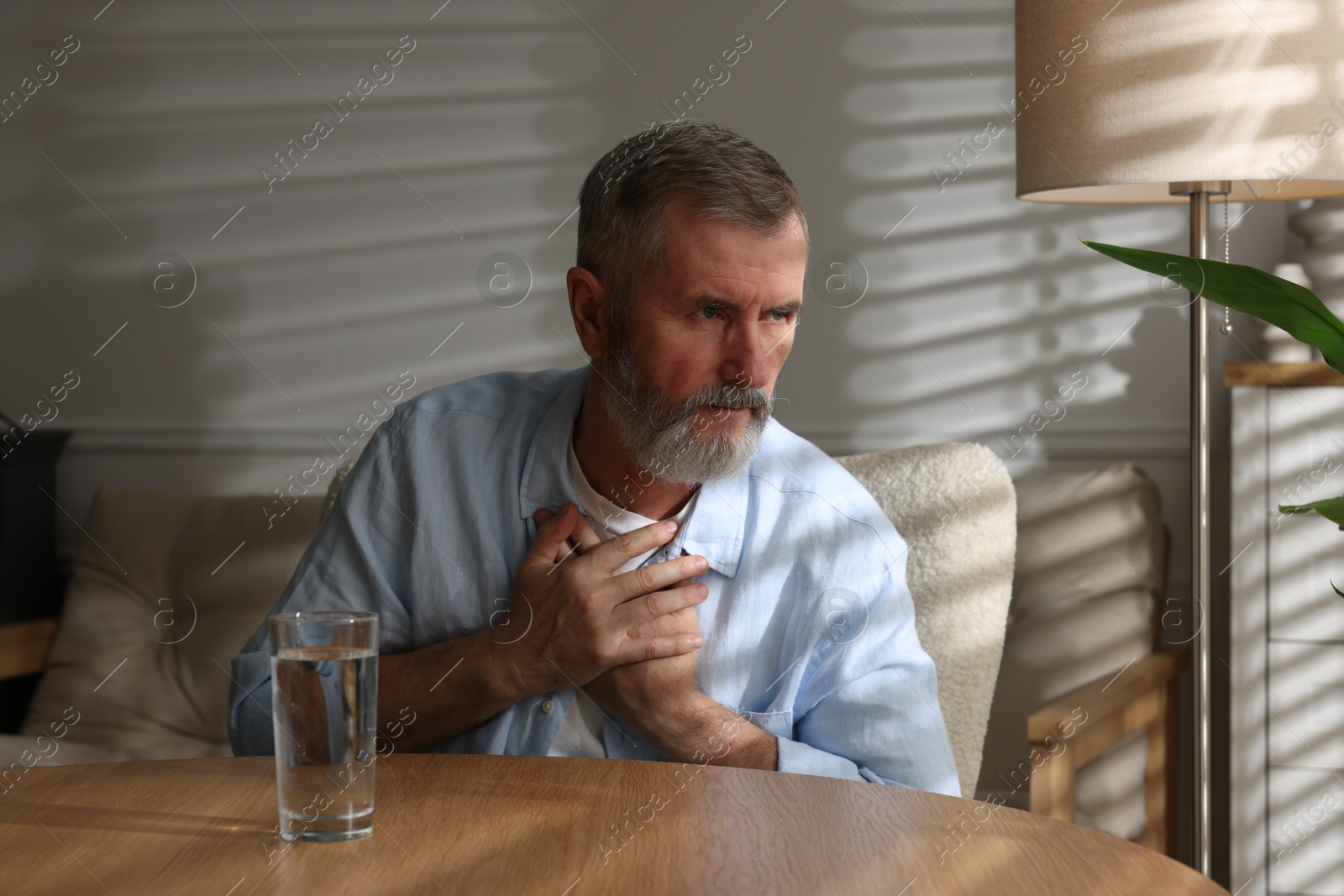 Photo of Senior man suffering from pain in chest at home