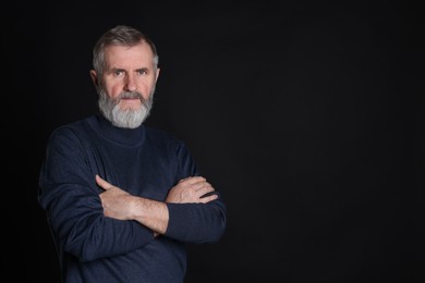 Portrait of senior man on black background, space for text