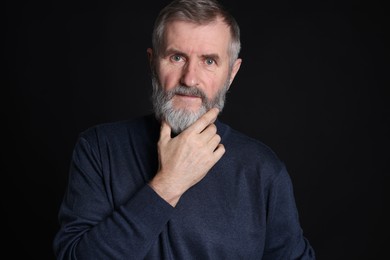 Portrait of senior man on black background