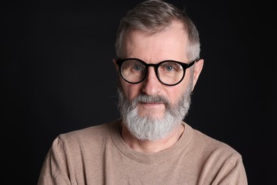 Senior man in glasses on black background