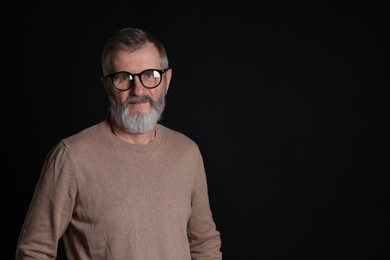 Photo of Senior man in glasses on black background, space for text