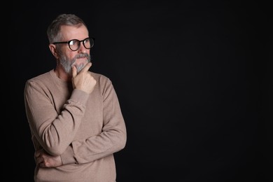 Photo of Senior man in glasses on black background, space for text