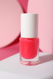 Stylish presentation of nail polish in bottle on pink background