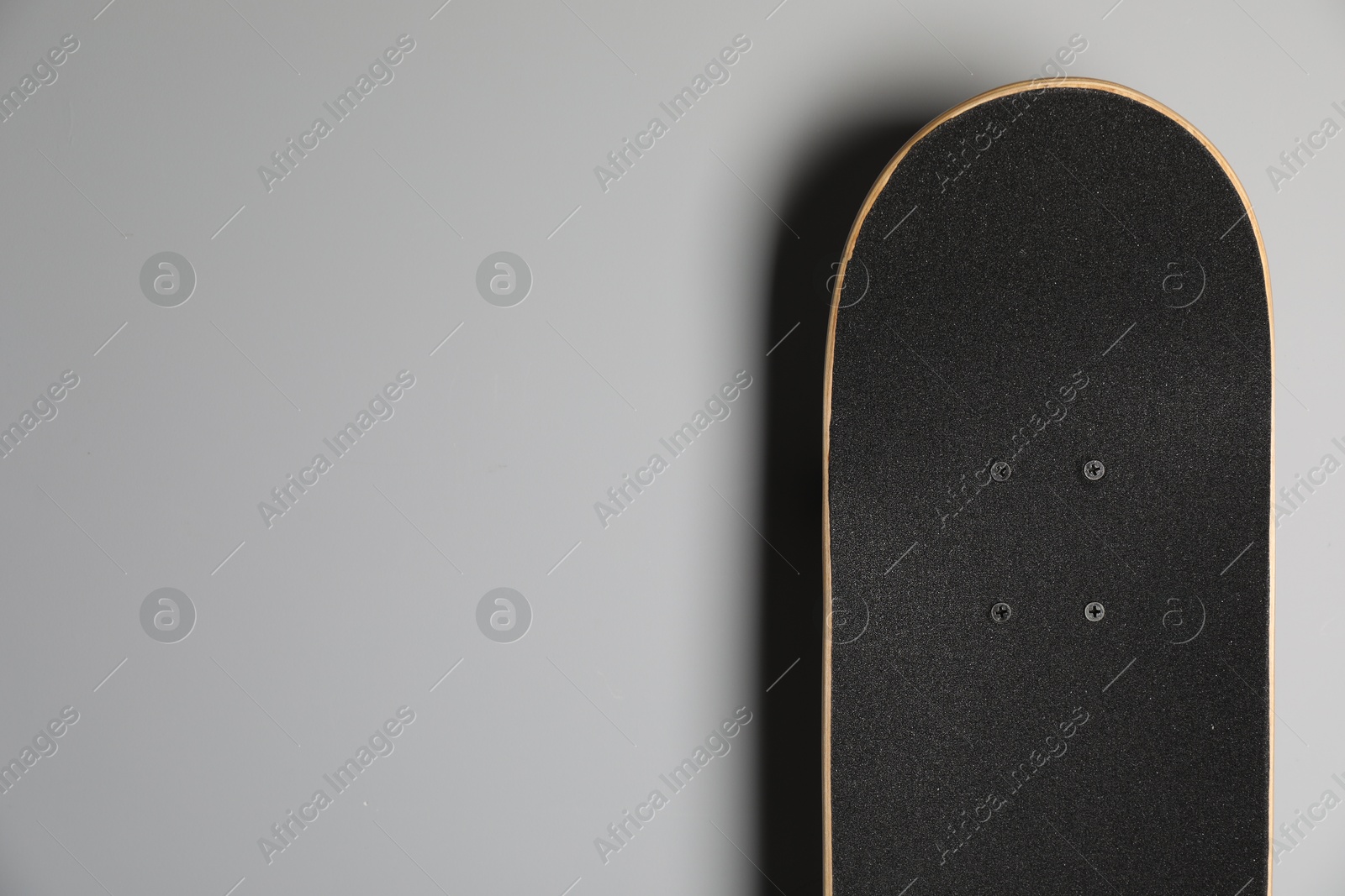 Photo of Modern skateboard on light grey background. Space for text