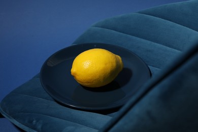 Photo of Plate with ripe lemon on blue chair