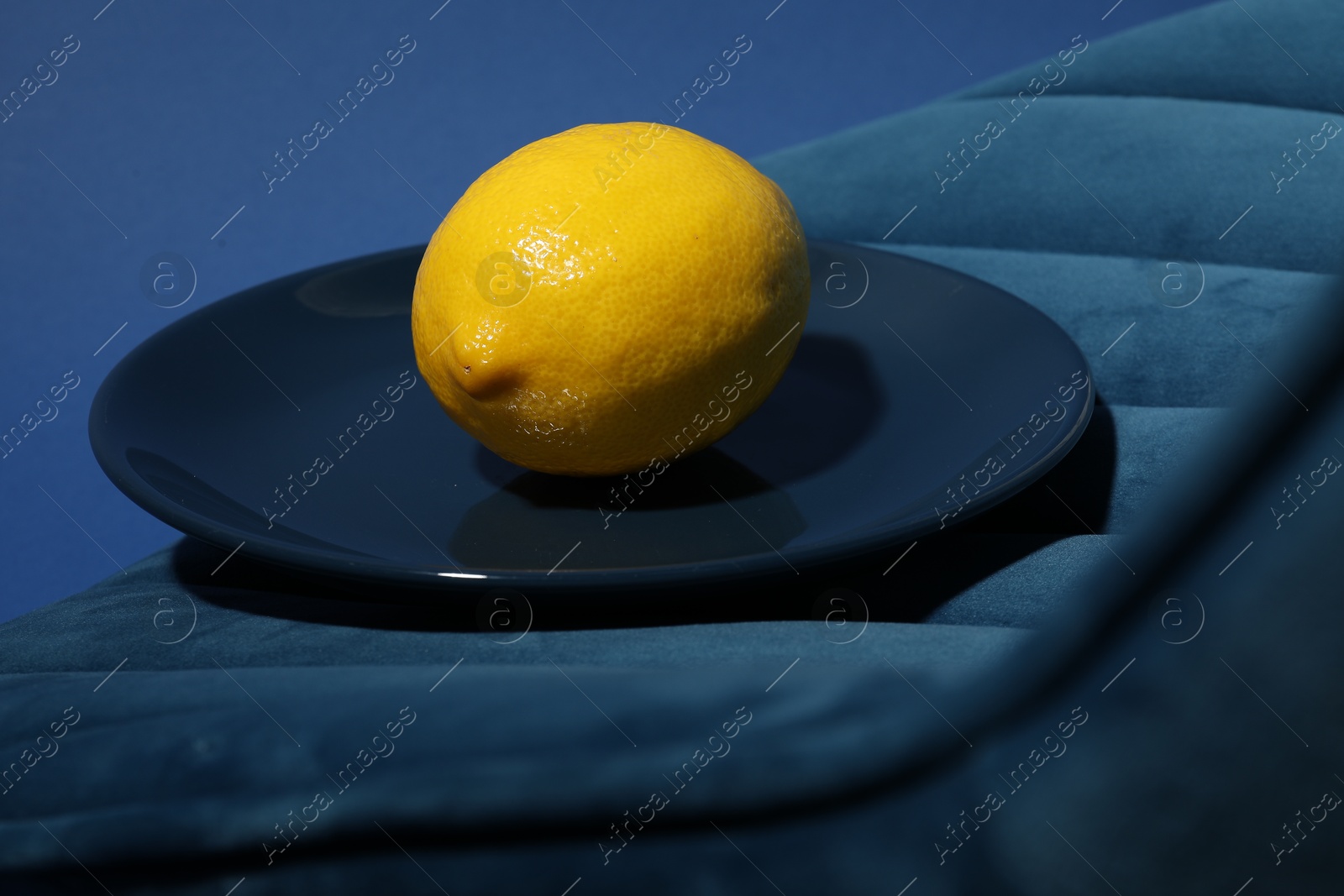 Photo of Plate with ripe lemon on blue chair