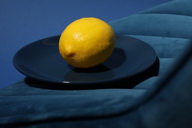 Plate with ripe lemon on blue chair