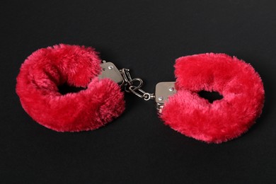 Photo of Bright fluffy handcuffs on black background. Sex toy