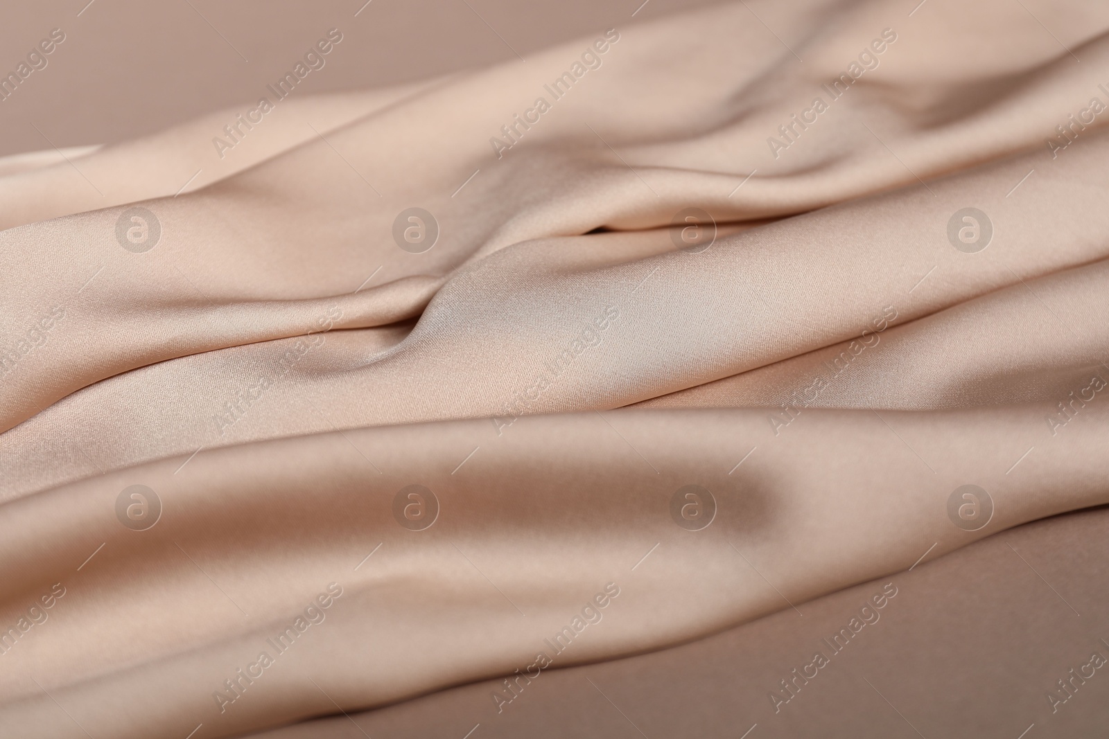 Photo of Beige silk fabric waving in air on color background