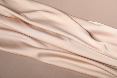 Beige silk fabric waving in air on color background