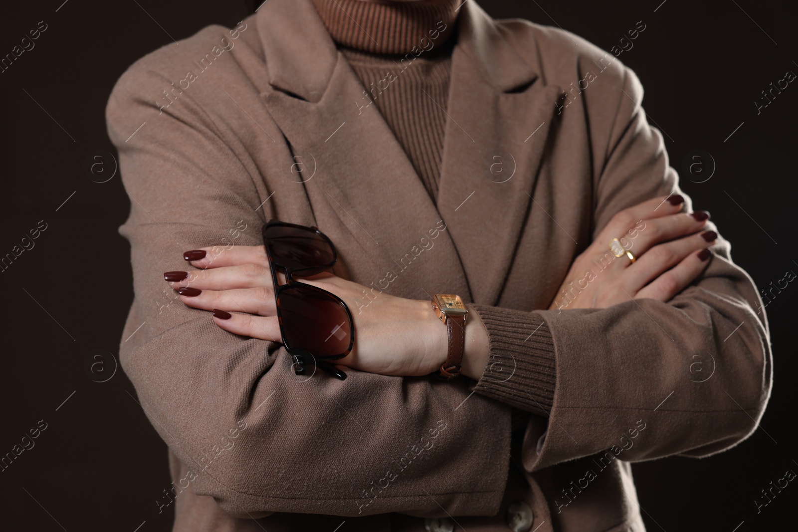 Photo of Woman with sunglasses in stylish coat on brown background, closeup