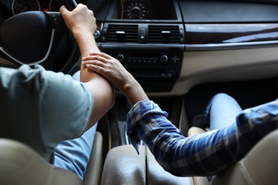 Lovely couple holding hands together while traveling by car, closeup