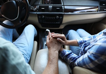 Lovely couple holding hands together while traveling by car, closeup