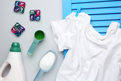 Photo of Different laundry detergents and t-shirt on grey background, flat lay