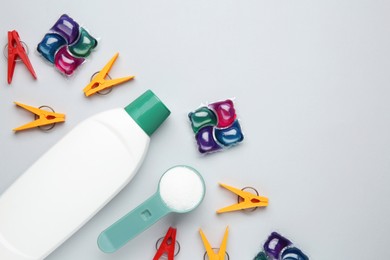 Photo of Different laundry detergents and clothespins on grey background, flat lay. Space for text