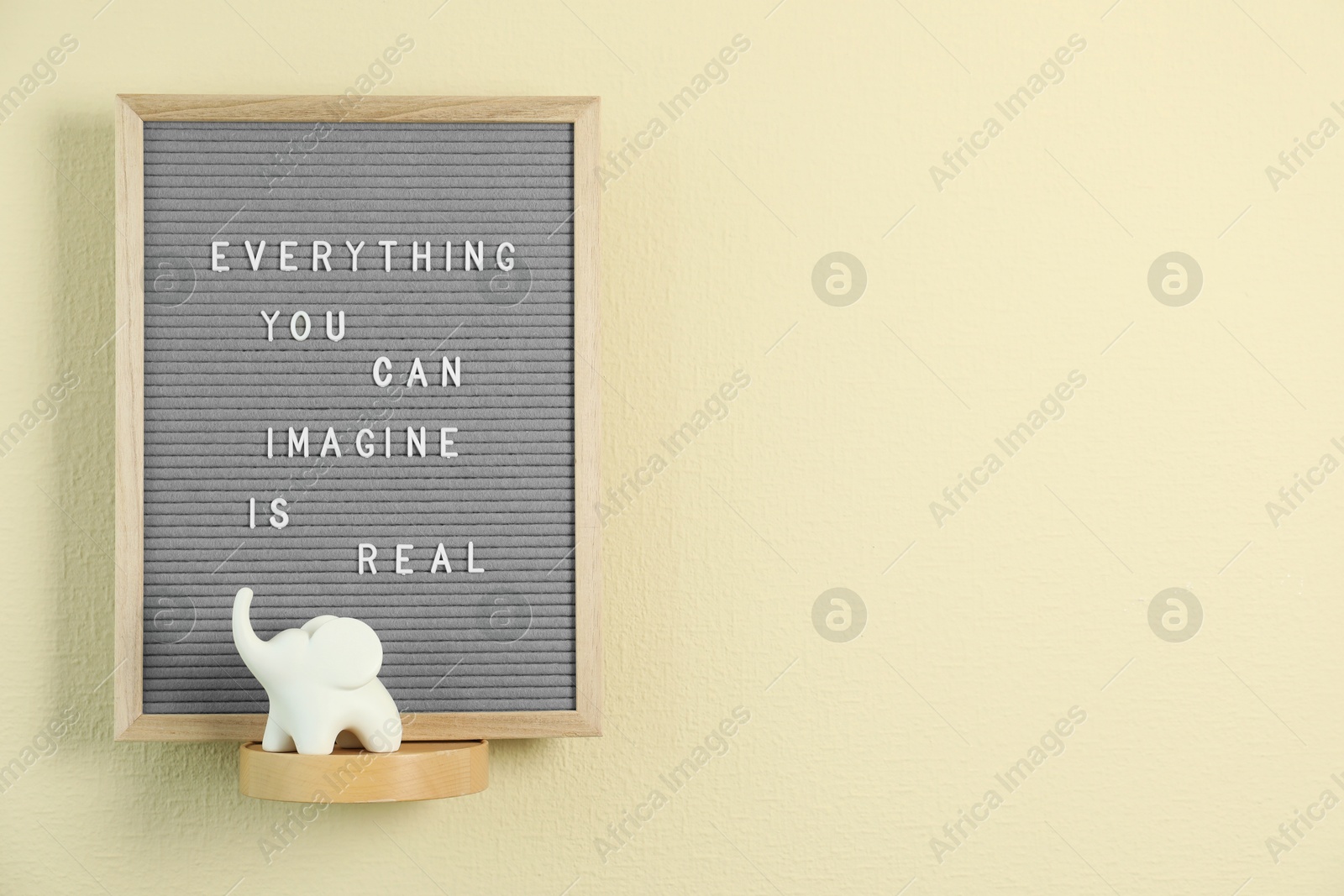 Photo of Letter board with phrase Everything You Can Imagine Is Real and decor element on beige wall. Space for text