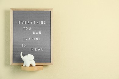 Photo of Letter board with phrase Everything You Can Imagine Is Real and decor element on beige wall. Space for text