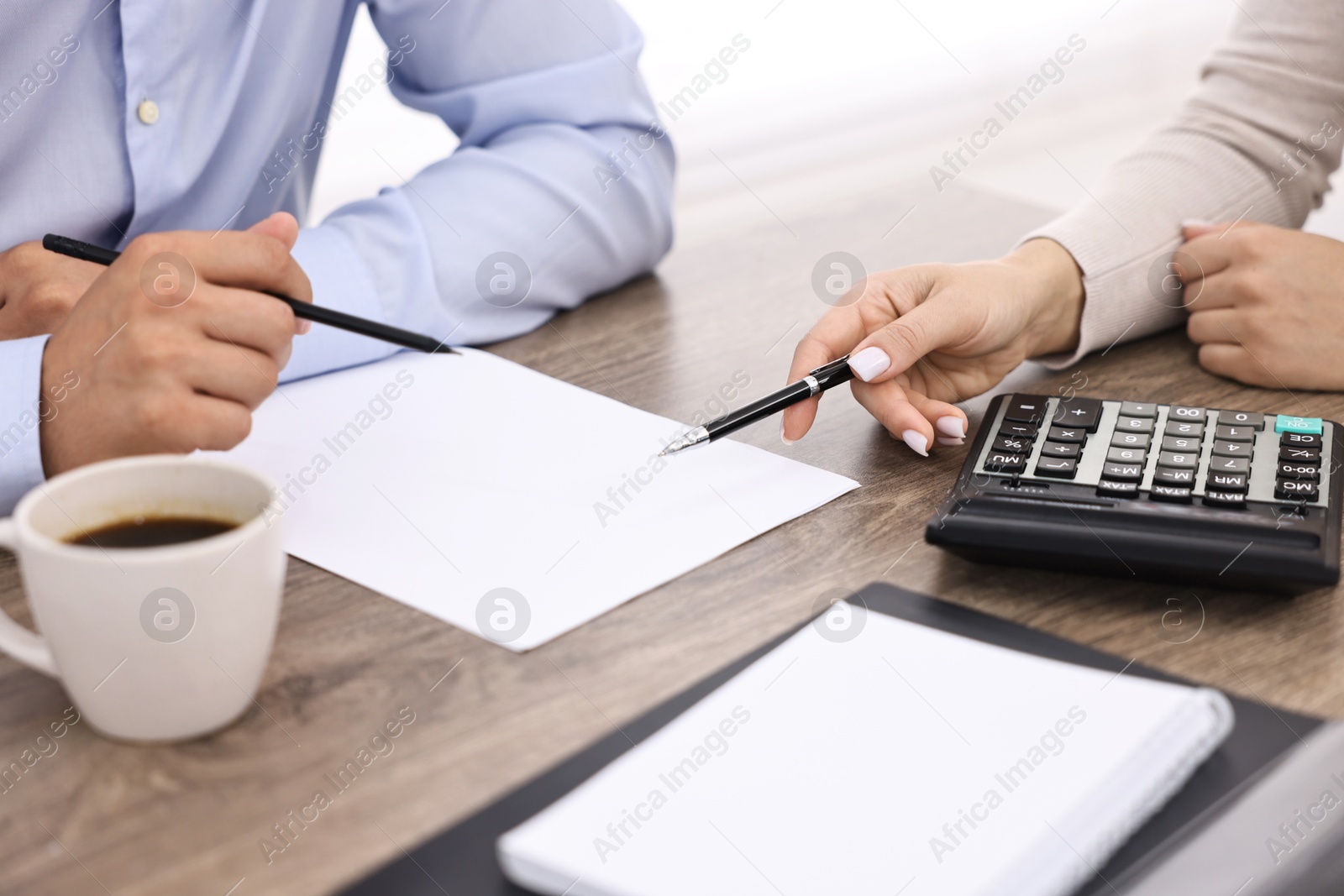 Photo of Banker working with client at wooden table in office, closeup