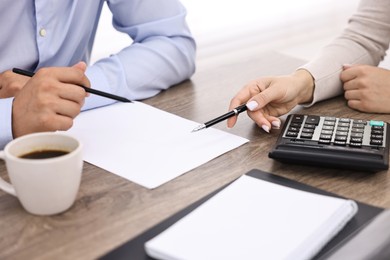 Banker working with client at wooden table in office, closeup