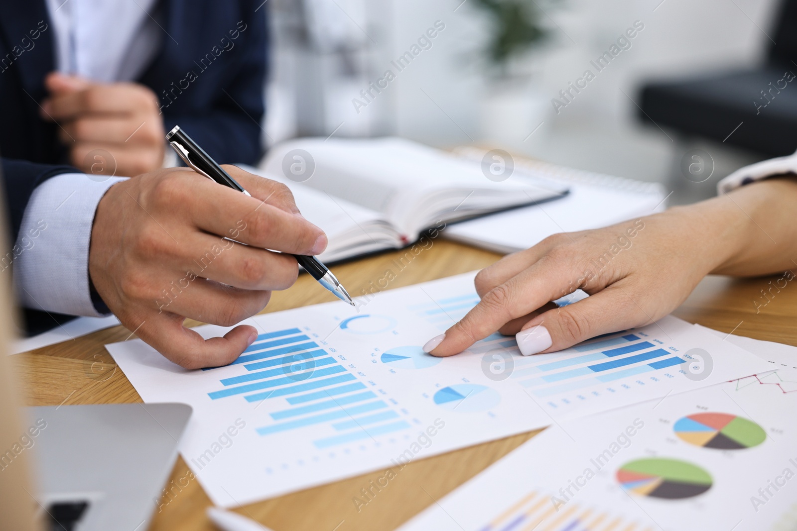 Photo of Banker working with client at wooden table in office, closeup