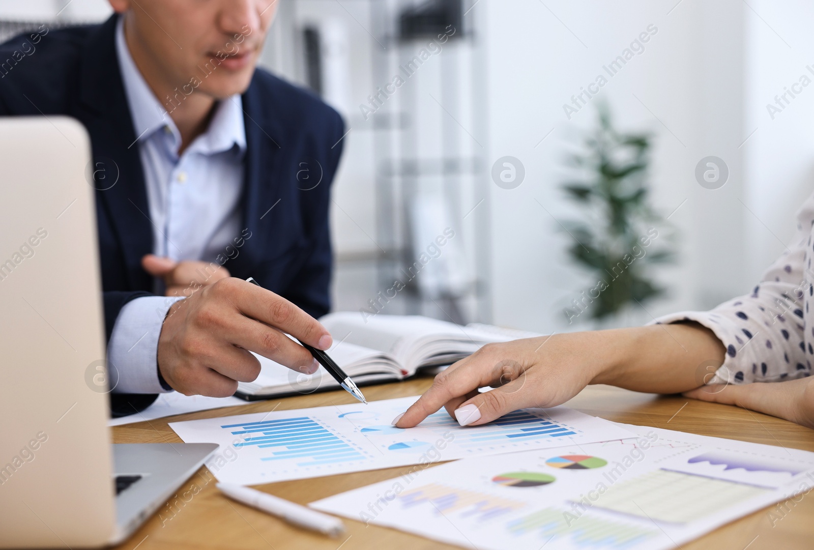 Photo of Banker working with client at wooden table in office, closeup