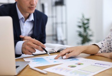 Banker working with client at wooden table in office, closeup