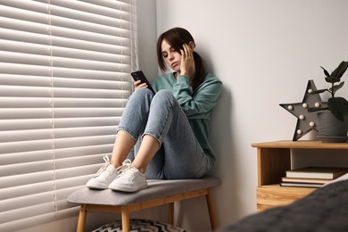 Photo of Loneliness concept. Sad teenage girl using smartphone at home