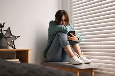 Photo of Loneliness concept. Sad teenage girl using smartphone at home