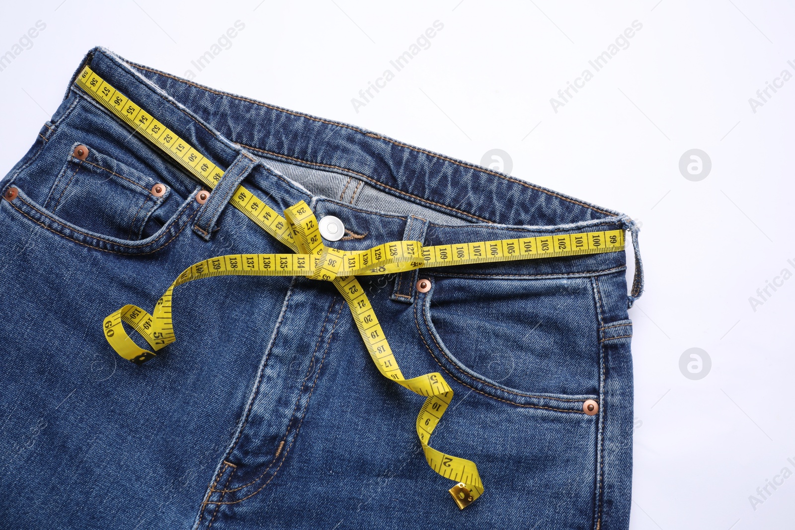 Photo of Jeans and measuring tape on white background, top view