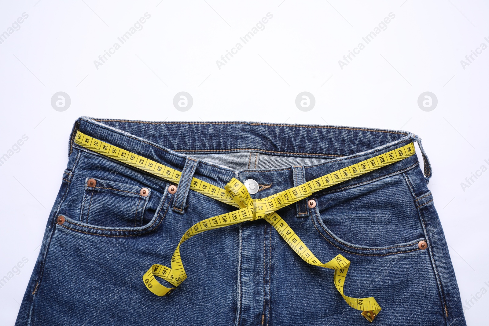 Photo of Jeans and measuring tape on white background, top view