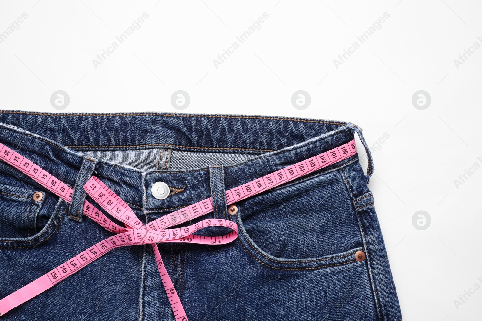 Photo of Jeans and measuring tape on white background, top view