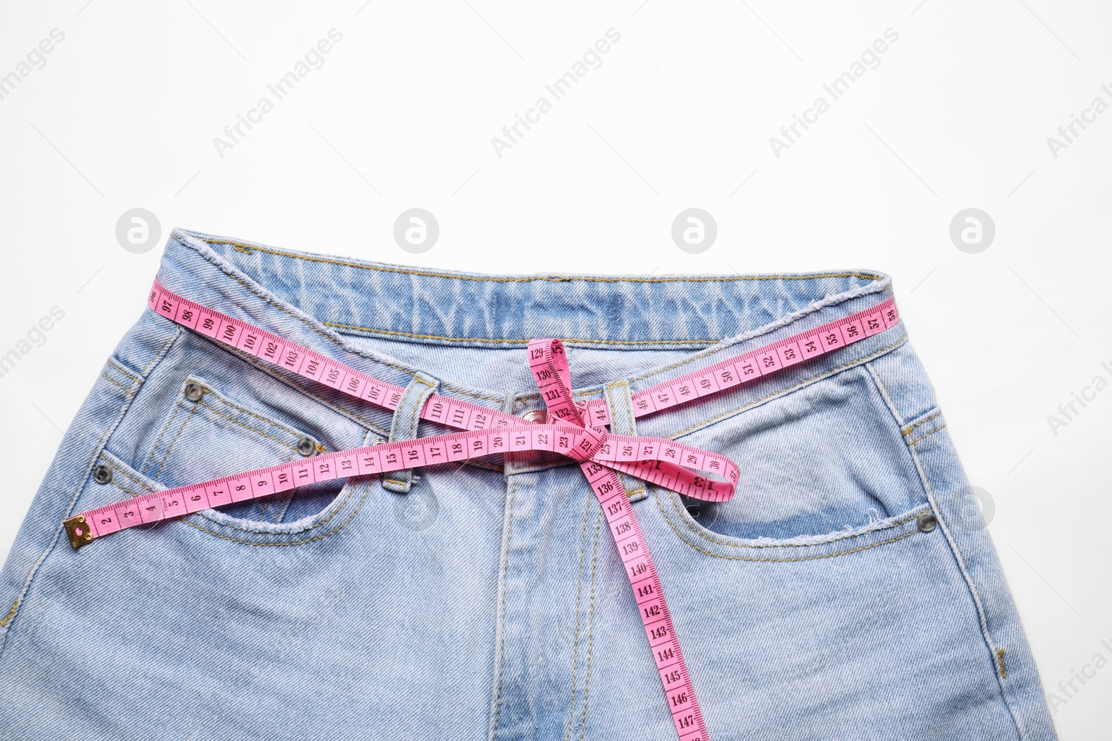 Photo of Jeans and measuring tape on white background, top view