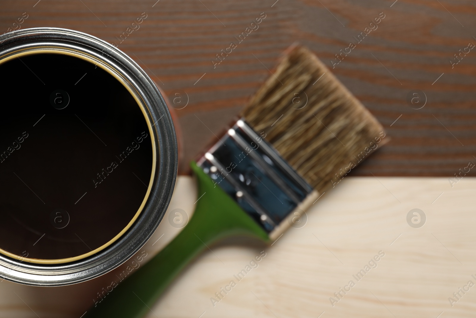 Photo of Applying walnut wood stain. Brush and can on wooden surface, flat lay