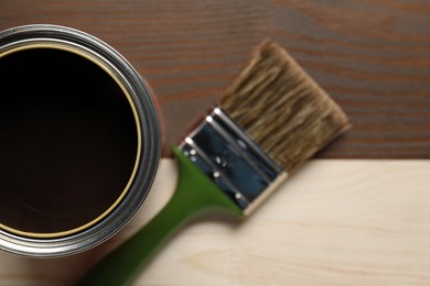 Photo of Applying walnut wood stain. Brush and can on wooden surface, flat lay