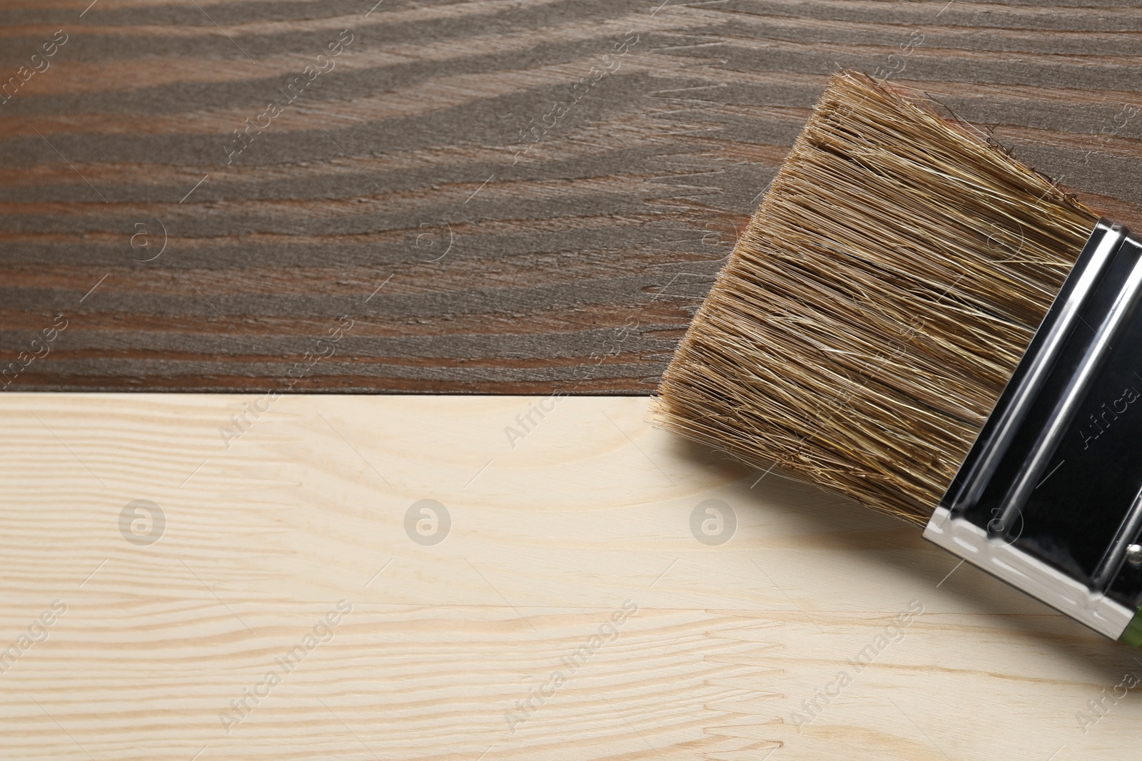 Photo of Applying walnut wood stain. Brush on wooden surface, top view. Space for text