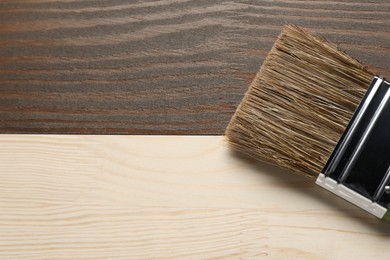 Photo of Applying walnut wood stain. Brush on wooden surface, top view. Space for text