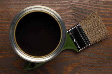 Photo of Applying walnut wood stain. Brush and can on wooden surface, flat lay