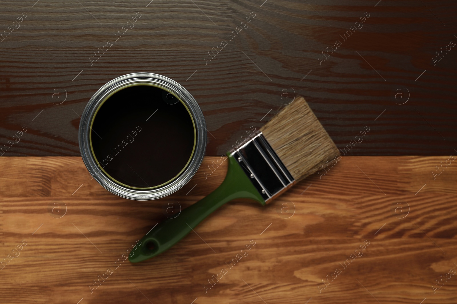 Photo of Applying walnut wood stain. Brush and can on wooden surface, flat lay